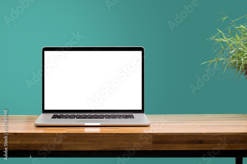 laptop on wooden desk with green wall background photo
