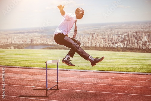 Composite image of businessman jumping a hurdle
