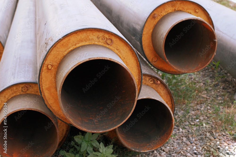 Steel water pipes with PVC isolation shell in stack on ground in construction site Steel water pipes with PVC isolation shell in stack on ground in construction site