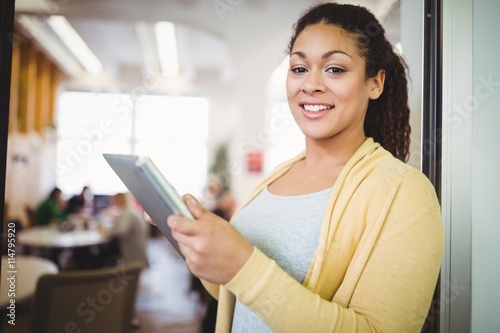 Happy businesswoman using digital tablet in office cafeteria