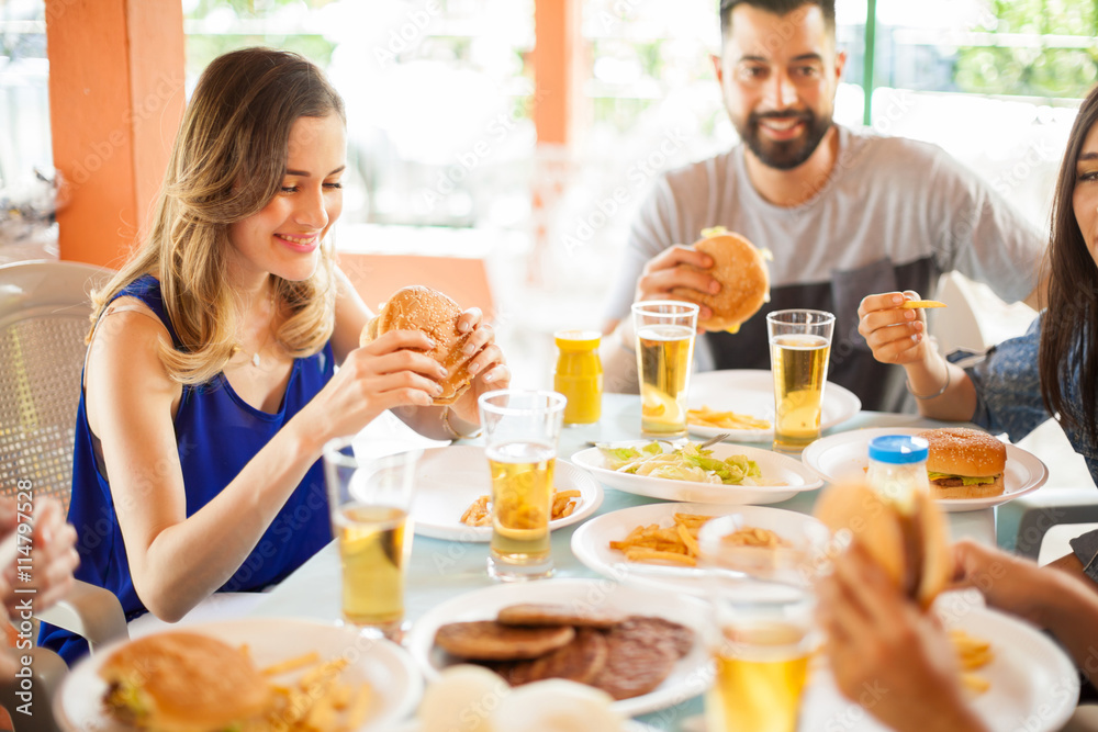 Cute woman eating a hamburger with friends