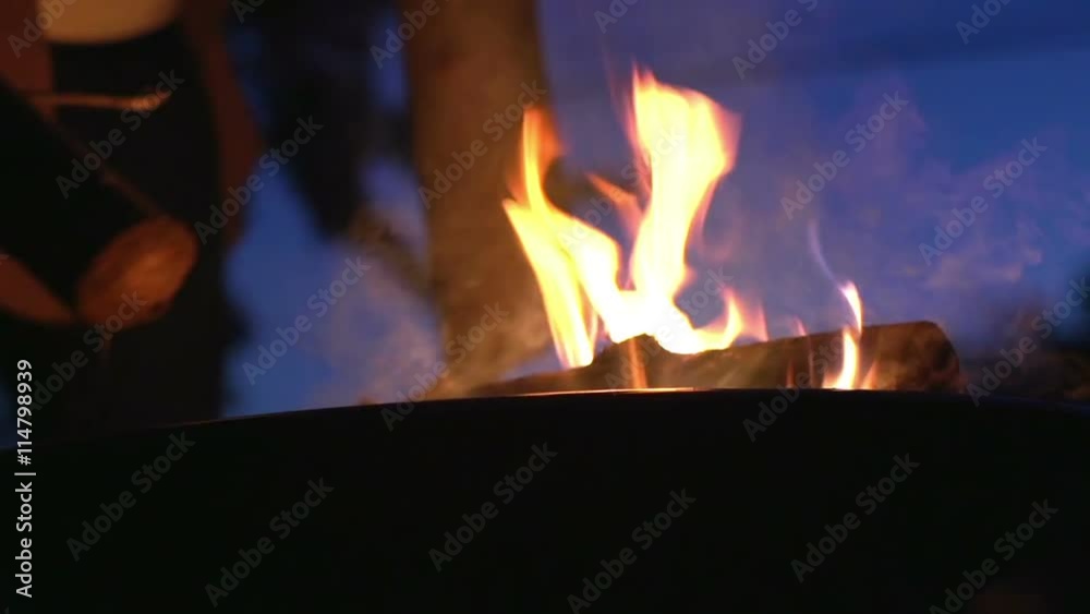 Log placed onto burning fire pit.
