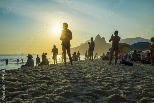 A crowd gathers on the rocks at Arpoador to watch the sun set behind the horizon at Two Brothers Mountain in Rio de Janeiro, Brazil