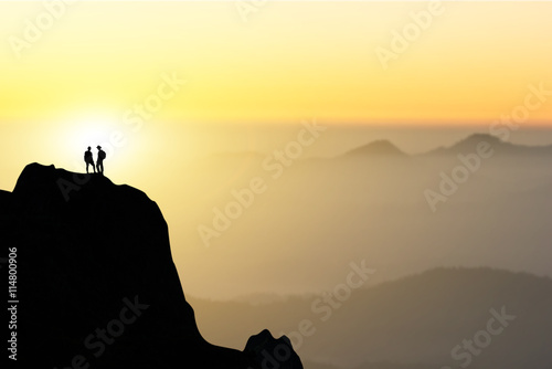 Two people silhouette of happy couple stand together on peak of