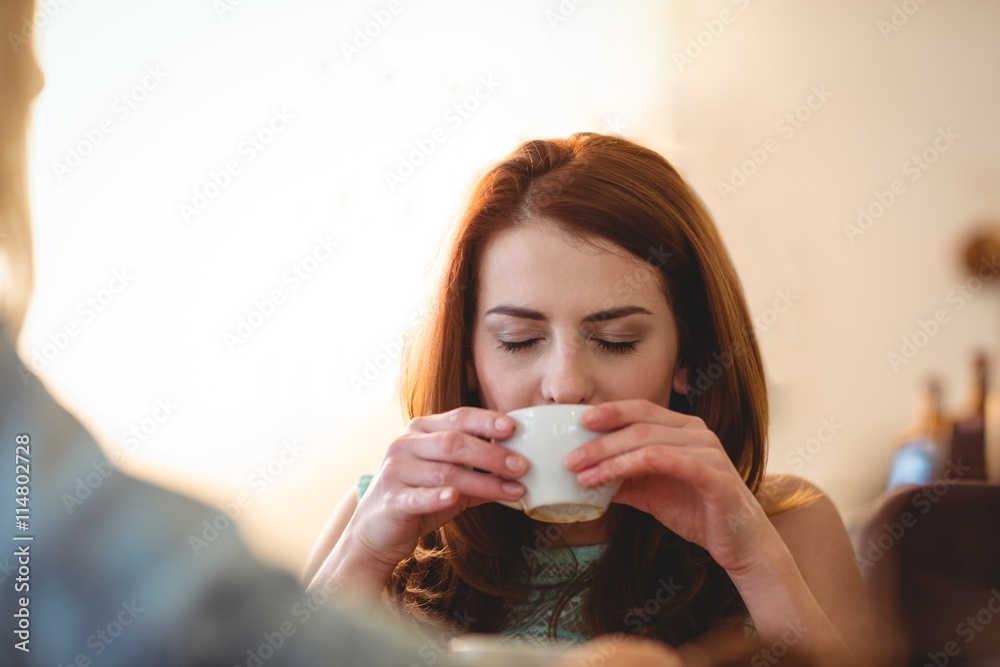 Beautiful woman sipping coffee with friend at cafe Beautiful woman sipping coffee with friend at cafe