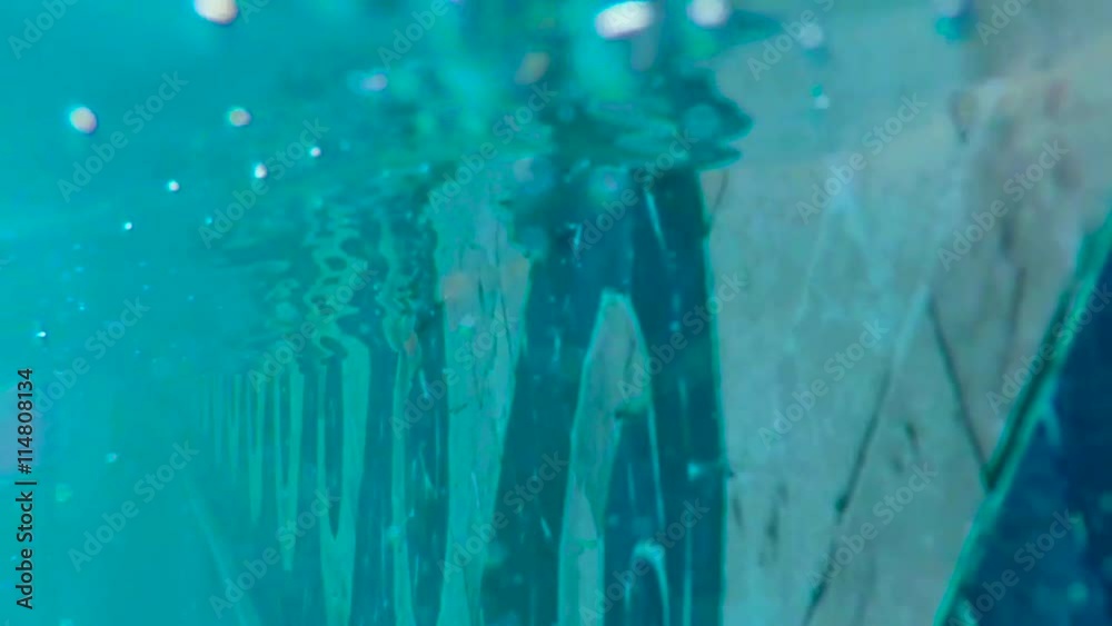 Close up of the side of a pool as the water level goes above and below the camera. Slow motion, 240fps