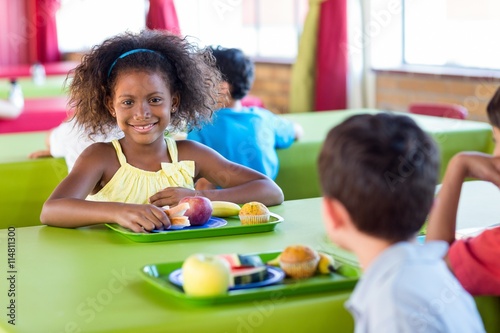 Smiling girl with classmates having meal photo