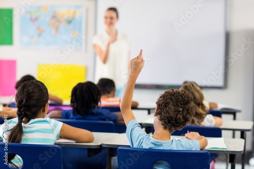 Teacher pointing boy with raised hand