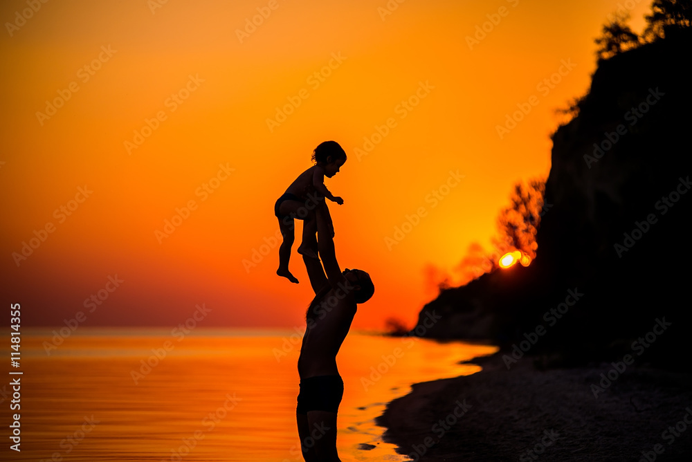 Father throwing his kid up in the air on the beach