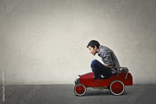 Teenager driving a toy car