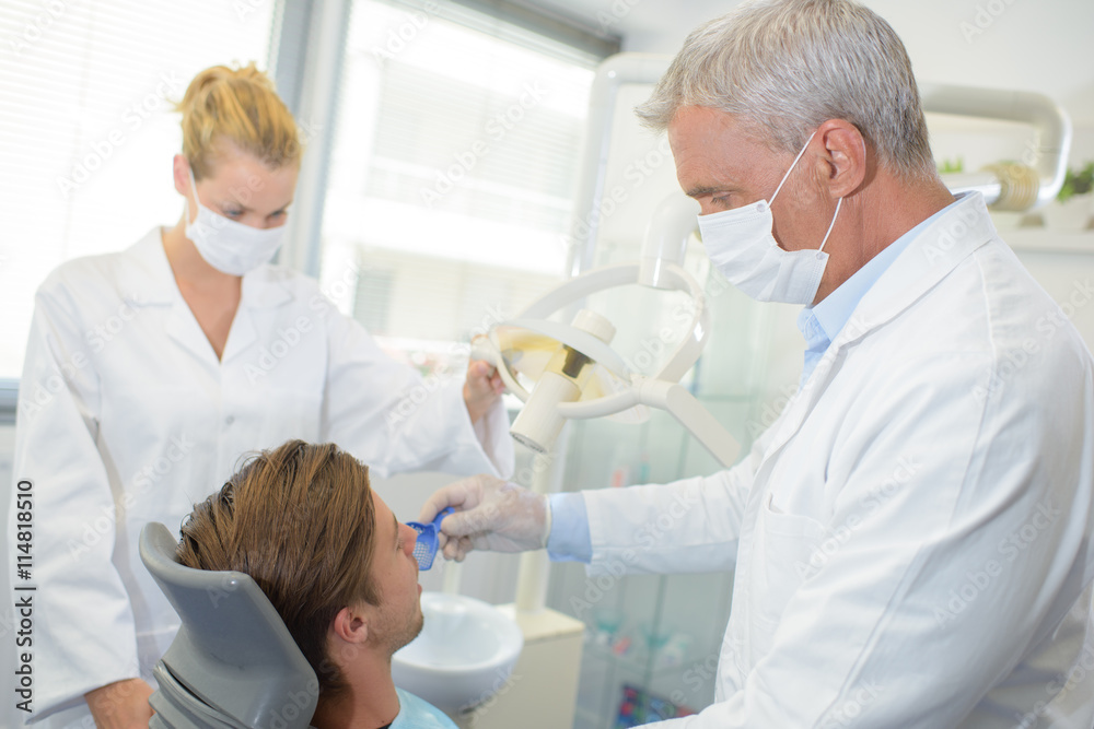 Obraz premium Dentist and assistant with male patient