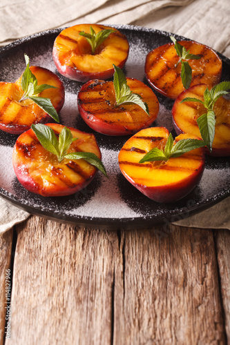Healthy Dessert: grilled Peaches with powdered sugar and mint close-up. vertical 