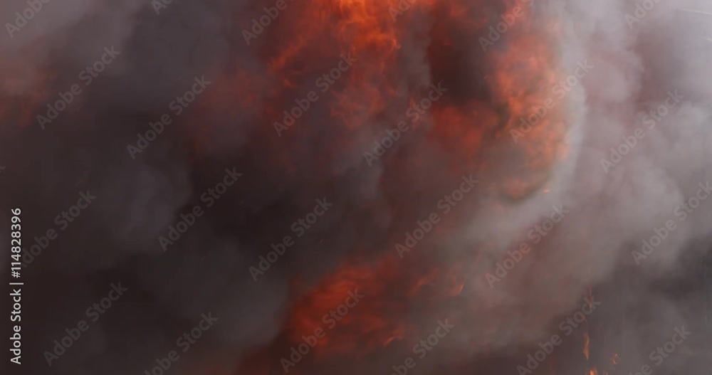 Burning structure with roiling smoke and bursts of flame