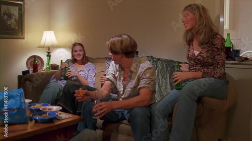 Two teenage couples sitting and drinking beer in a living room