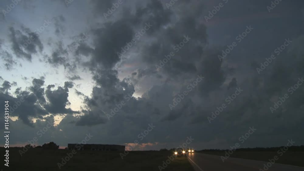 Left pan over dissipating storm clouds over fields along a rural road at evening Left pan over dissipating storm clouds over fields along a rural road at evening