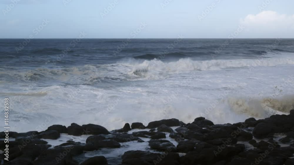 Foaming waves crashing over dark rocks close to the camera Foaming waves crashing over dark rocks close to the camera