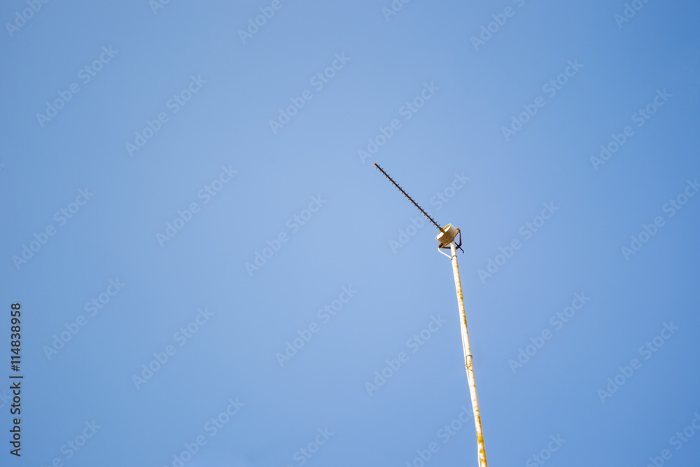 Old TV antenna in blue sky.