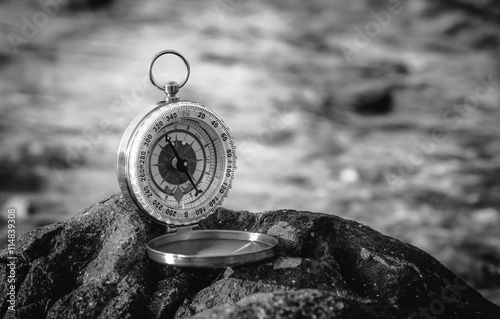 Black and white analogical compass abandoned on the rocks with b