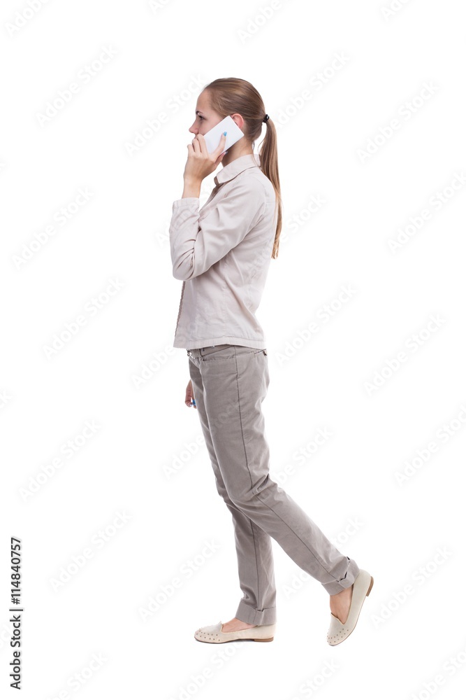 side view of a woman walking with a mobile phone. back view ofgi side view of a woman walking with a mobile phone. back view ofgi
