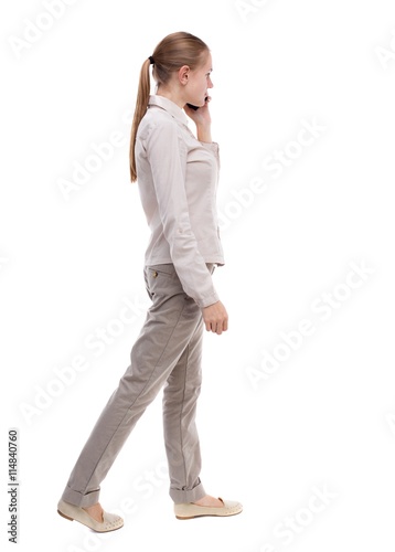 side view of a woman walking with a mobile phone. back view ofgi