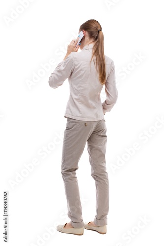 back view of a woman talking on the phone. backside view of person. Rear view people collection. Isolated over white background. A girl in a white jacket is white smartfonfon pressed to his ear.