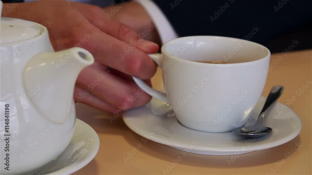male hands close up pour tea into a cup and mixing spoon male hands close up pour tea into a cup and mixing spoon