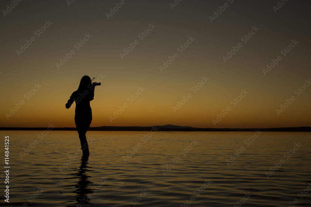 Turkey, women silhouette violin Salt lake at sunset