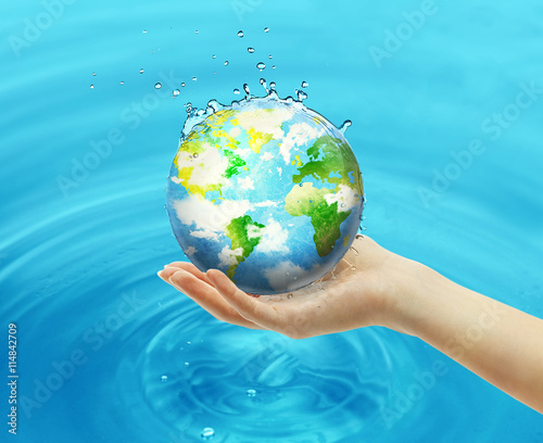 Female hand holding globe on blue water background