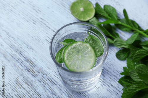 Infused lime water with mint on wooden background