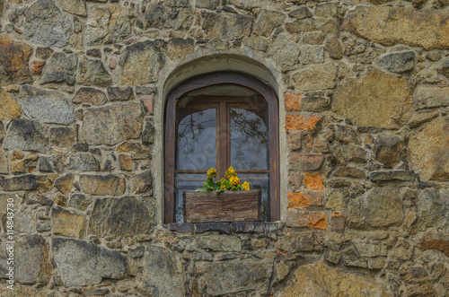 okno w kamiennym murze wieży. 