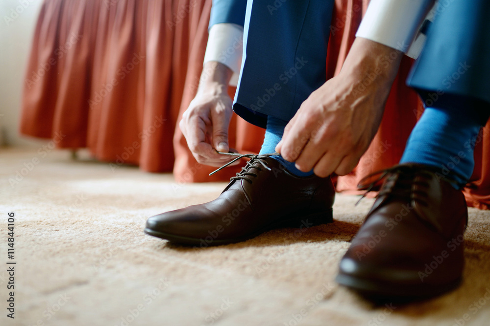 Groom is wearing shoes indoors. Male portrait of handsome guy. Beautiful model boy in colorful wedding clothes. Man is posing