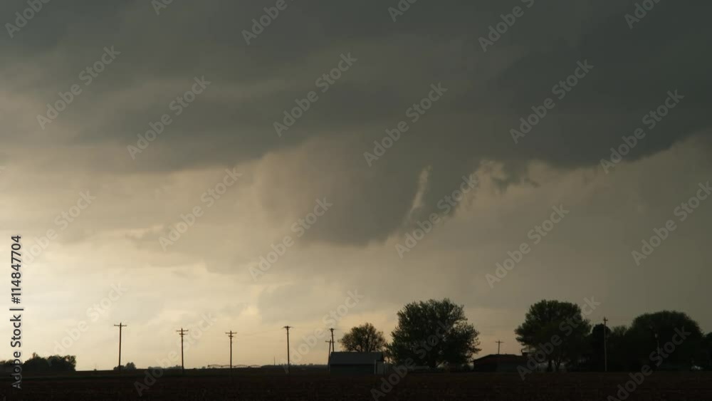 Time-lapse gray clouds hint at funnel shapes above a prairie farm at twilight Time-lapse gray clouds hint at funnel shapes above a prairie farm at twilight