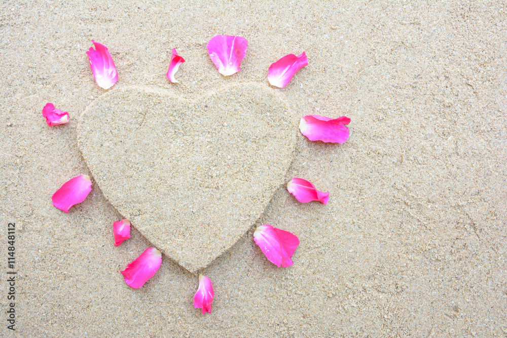 Heart shape and pink rose petal with sand background