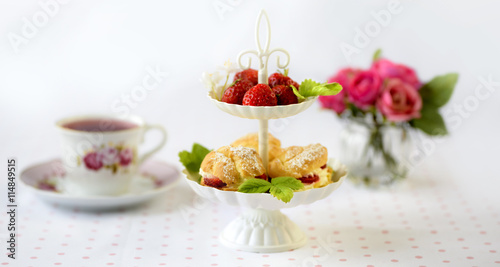 Cream puffs or profiterole filled with whipped cream served with strawberries in plateau on a breakfast table
