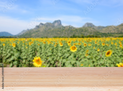 Wood table top and blur sunflower field background
