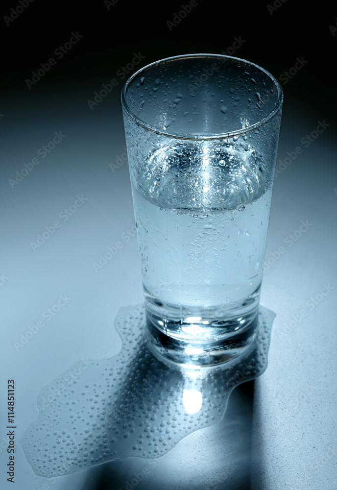 Glass and some mineral water on blue background Glass and some mineral water on blue background