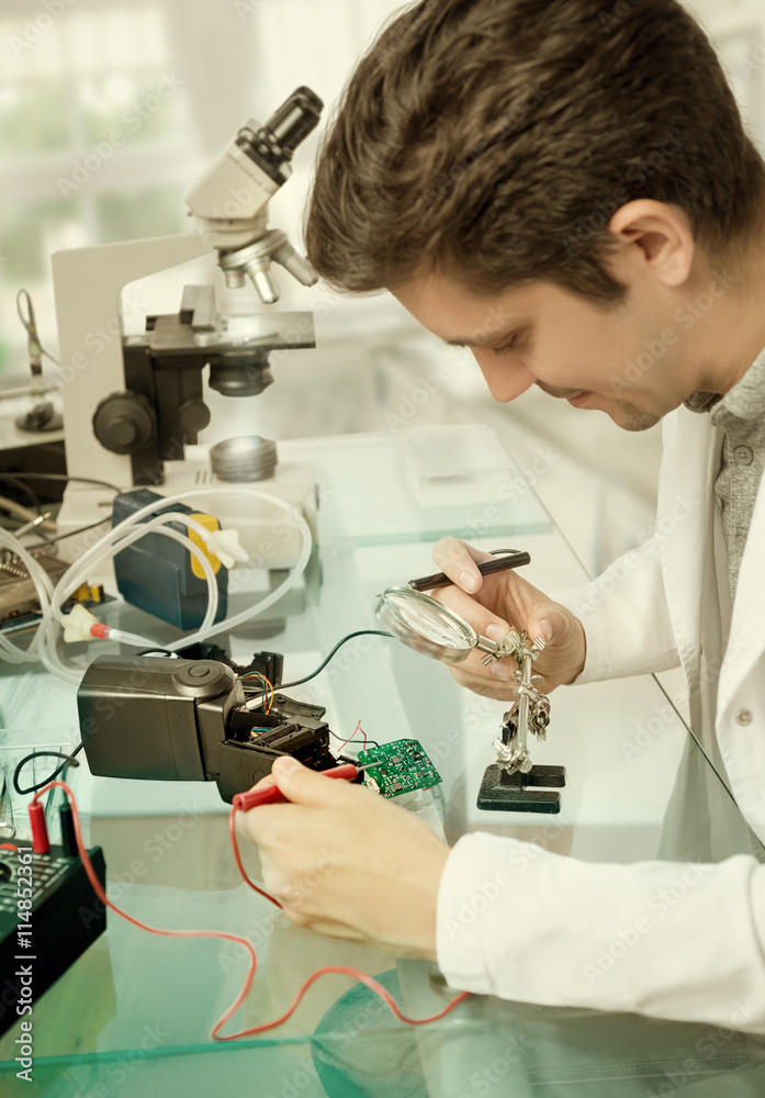 Young male tech repairs flash electronic unit Young male tech repairs flash electronic unit