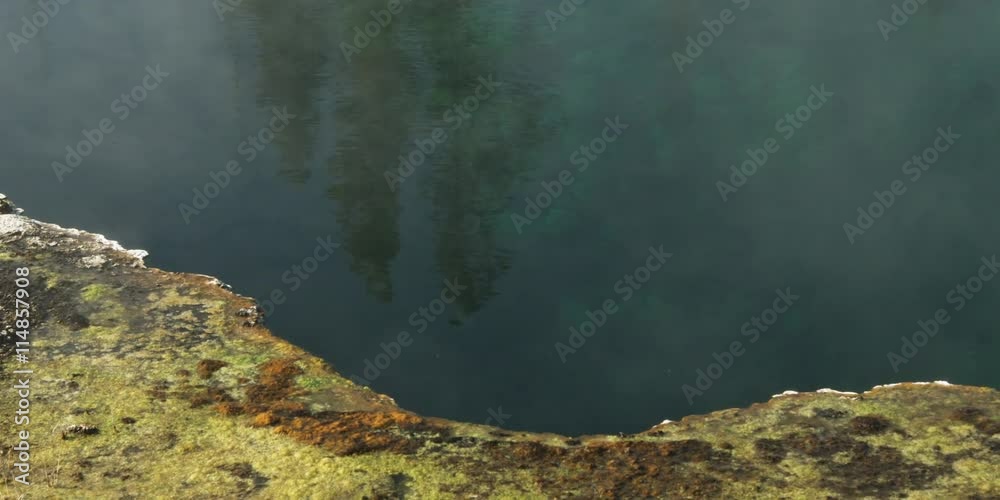 Right pan over the mineral-crusted edge of a steaming geothermal pool