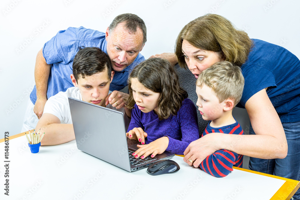 Family gathered around laptop looks at shocking content on internet, studio shot. Family gathered around laptop looks at shocking content on internet, studio shot.