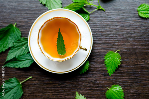 herbal nettle tea in a porcelain Cup on a dark wooden background