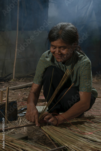 Asian elderly woman weaves a roof.