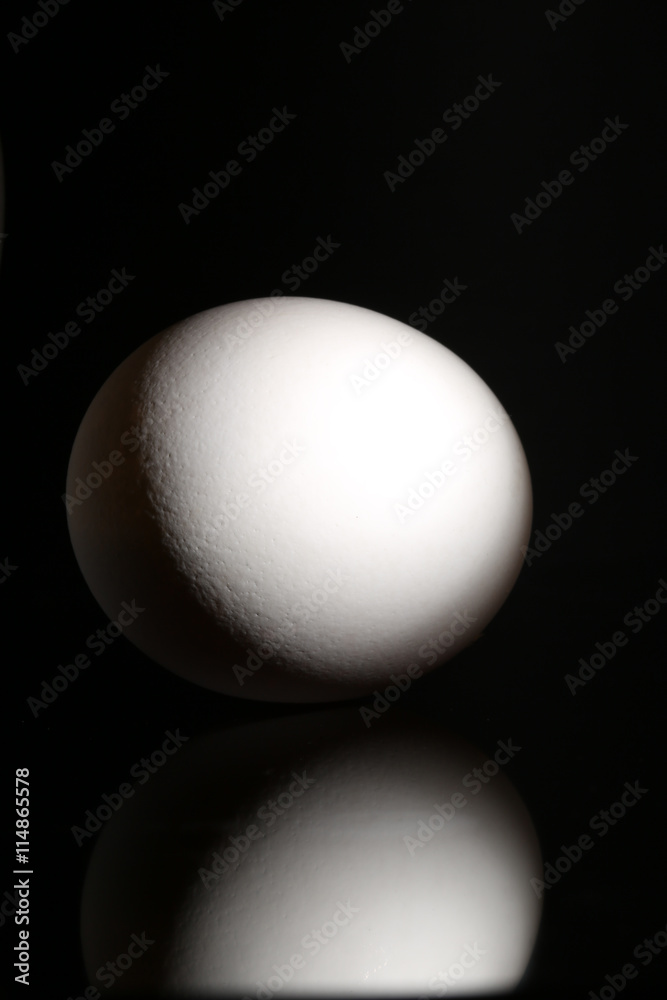 White egg on black background with reflection at studio
