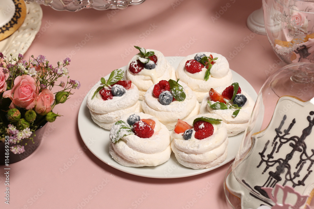 Meringue nests with strawberry cream, fresh strawberries, raspberries, blueberries and a mint leaf