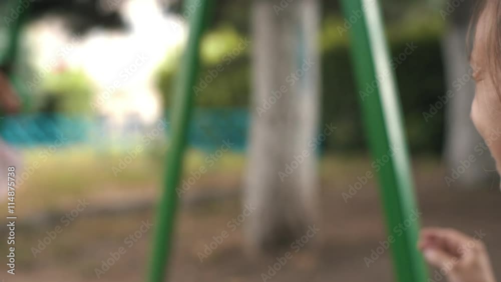 Woman rocking her infant daughter on a swing on a Sunny summer day
