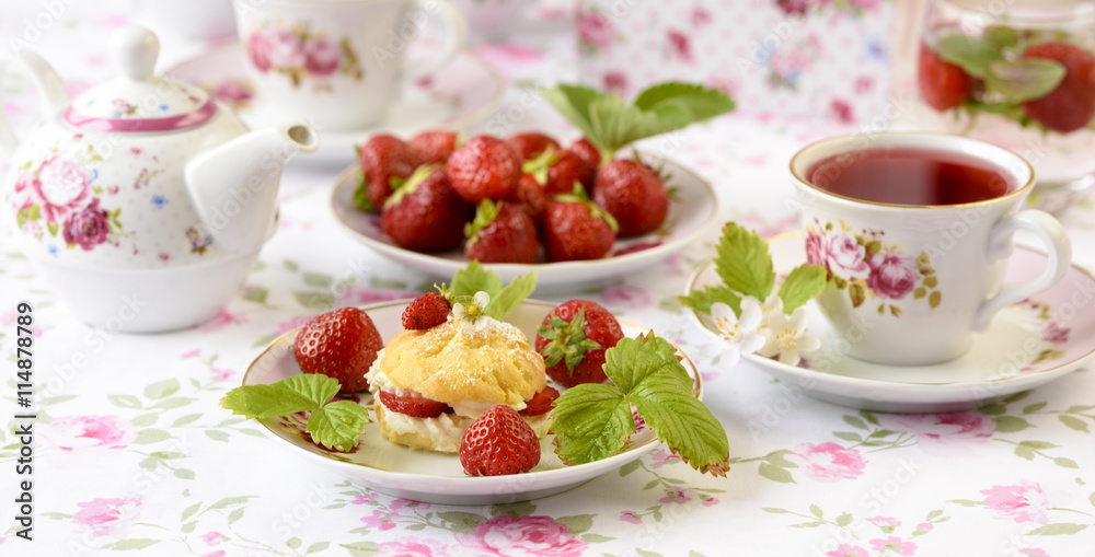 Cream puffs or profiterole filled with whipped cream, powdered sugar topping served with strawberries on the table Cream puffs or profiterole filled with whipped cream, powdered sugar topping served with strawberries on the table