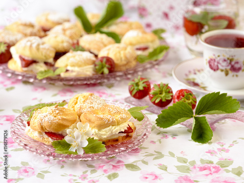 Cream puffs or profiterole filled with whipped cream served with strawberries on a breakfast table