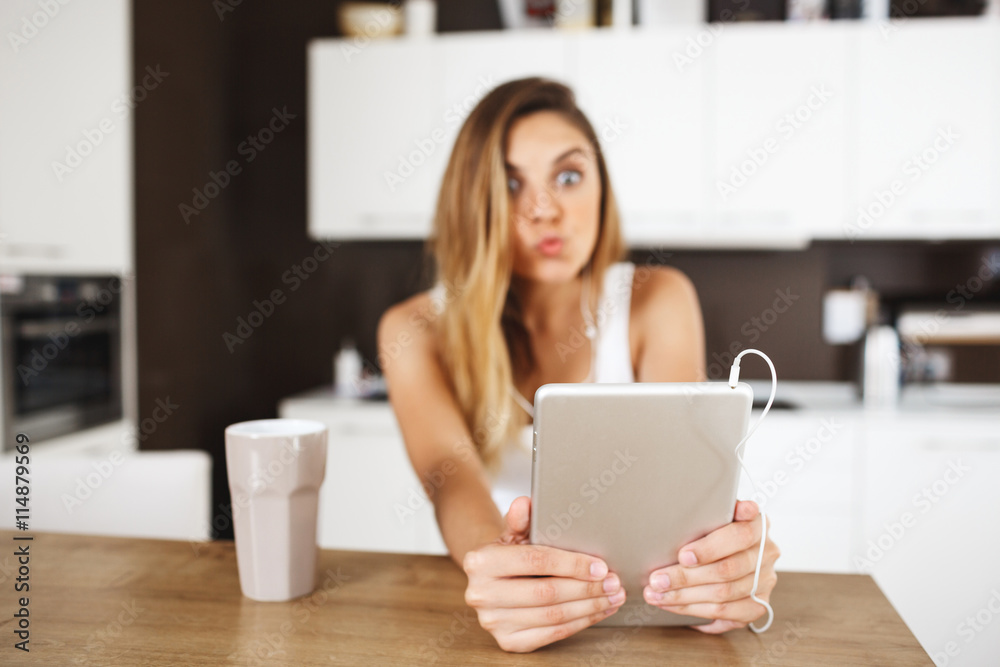 Attractive young girl sitting at dinner table and making funny selfie Attractive young girl sitting at dinner table and making funny selfie