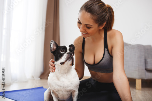 Beautiful fitness girl sitting on floor with dog