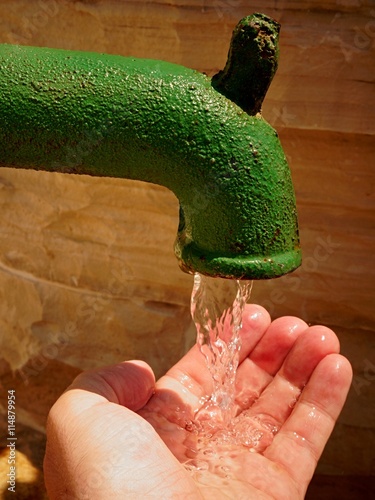 Male adult hand filled with fresh water from green water tap