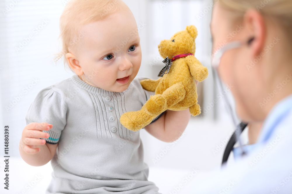 Pediatrician is taking care of baby in hospital. Little girl is being examine by doctor with stethoscope. Health care, insurance and help concept. Pediatrician is taking care of baby in hospital. Little girl is being examine by doctor with stethoscope. Health care, insurance and help concept.
